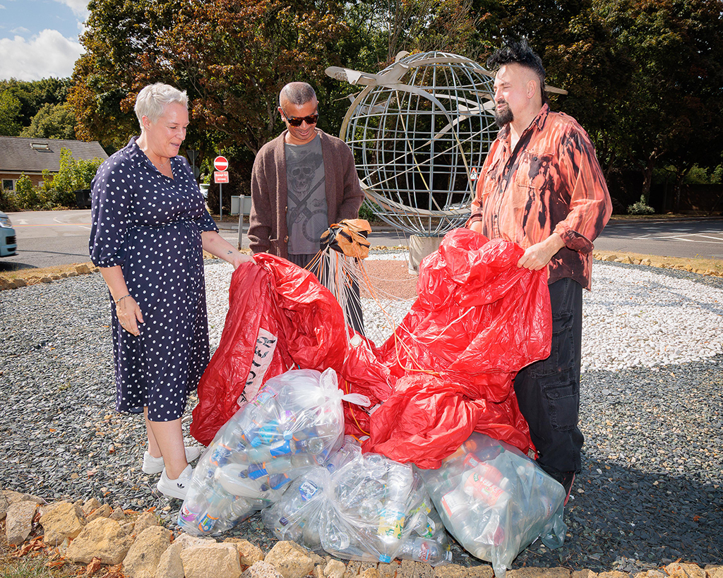 Pictured, are Lorna Nunn, Station Environmental Protection Officer, on the left then VIN + OMI, centre and right, standing in front of the Station Gate sculpture.